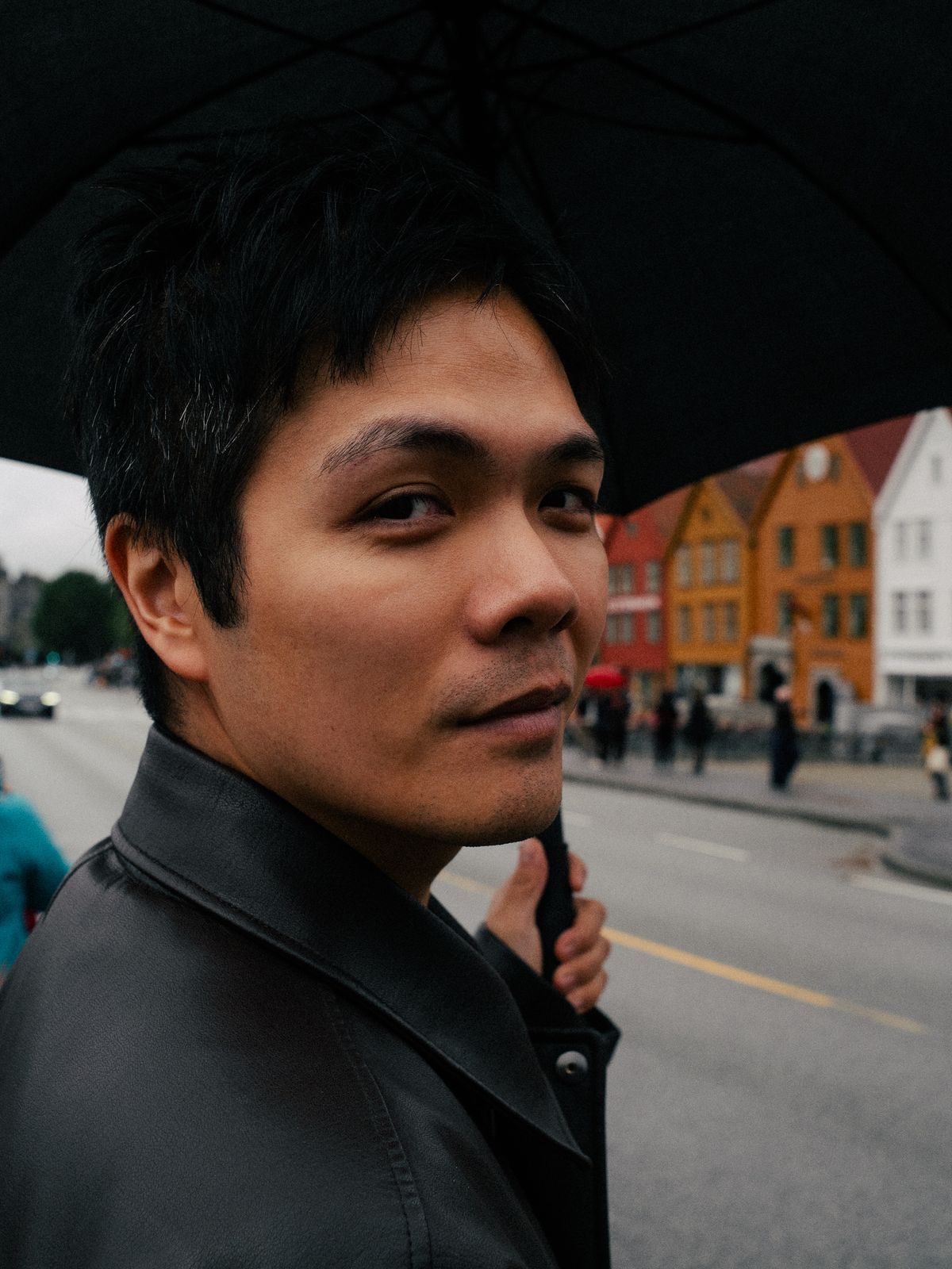 Portrett av Hien under en svart paraply i en gate i Bergen